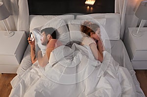 Man using smartphone while girlfriend is sleeping