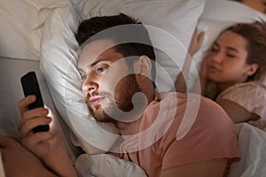 Man using smartphone while girlfriend is sleeping