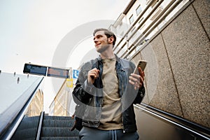 Man using smartphone while going down to subway on escalator