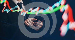Man using smartphone with graphs analysis candle line and foreign currency rate on bokeh colors light. Manager analyzing