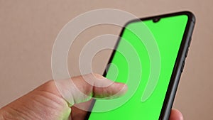 Man using a smartphone with a green screen. Hand with Mock-up Screen Chroma Key smartphone screen