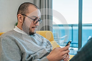 Man using smartphone at home, browsing internet news, social media or downloading application or app