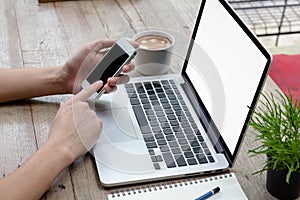 Man using smartphone with laptop and coffee on table