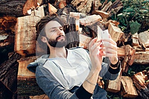 Man using smartphone on pile of wood