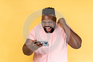 Man using smartphone and playing mobile game with excited positive face, happy to win, clenched fist