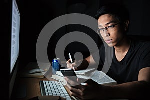 Man using smartphone while studying in the evening at home