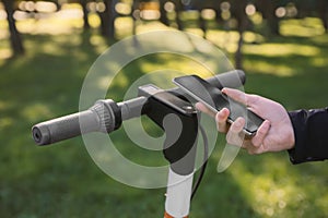 Man using smartphone to pay and unblock rental electric scooter outdoors, closeup photo