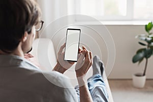 Man using smartphone, white blank empty screen. Young man student texting on mobile phone indoor