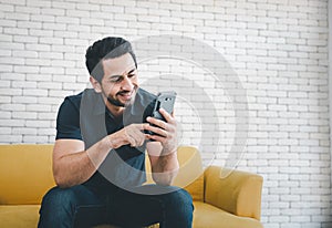 Man using smartphone on yellow sofa