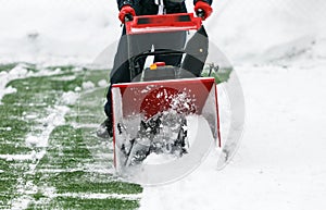 Man using a snowblower to remove large amounts of snow on a football field. A man cleans snow with a snow-removing machine