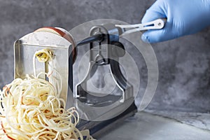 Man using spiralizer to cut apple into strips.