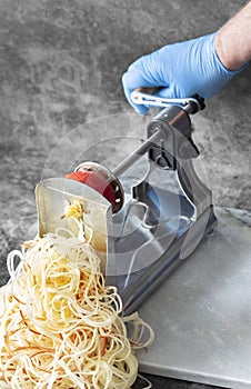 Man using spiralizer to cut apple into strips.