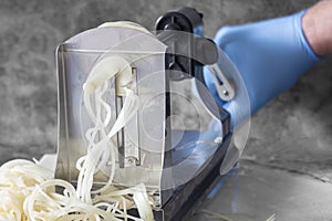 Man using spiralizer to cut potato into strips.