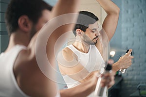 Man using spray deodorant on underarm for bad smell
