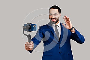 Man using stedicam and phone for livestream, waving hand to followers, content for business vlog. photo