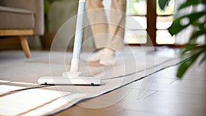 A man using stick vacuum cleaner to clean the carpet in living room. house cleaning