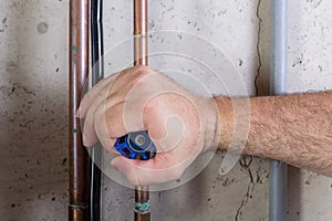 Man using strength to turn a water valve on a pipe