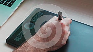 Man using stylus from drawing tablet. Creation of digital illustration. Hand close-up. Top view. Concept of retouching