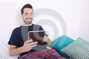 Man using tablet on bed.