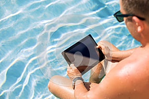 Man using tablet computer by the pool