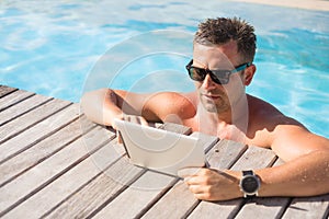 Man using tablet computer while relaxing in the pool