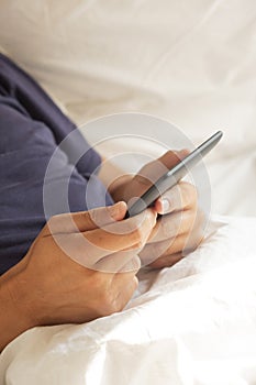 Man using a tablet or an e-reader in bed