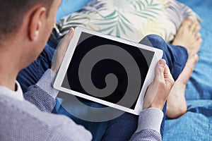 Man using a tablet lying on a couch photo