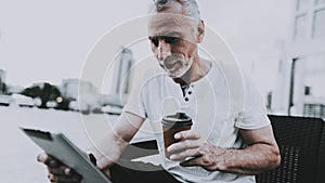 Man is Using a Tablet PC and Drinking a Coffee