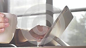 Man using tablet. Person drinking morning coffee and checking internet.