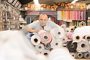 Man using tablet selects fabric from storage shelves