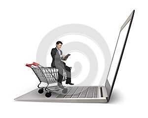 Man using tablet sitting on shopping cart with laptop