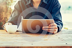 Man using tablet on table in coffee shop with vintage toned filter.