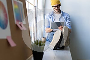 Man using Tablet for Work and Browsing Information, Young creative manager sitting by the window.