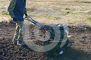 man using a tillerblock plows the ground for planting in the spring
