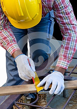 Man using a try square to mark and measure a wooden board