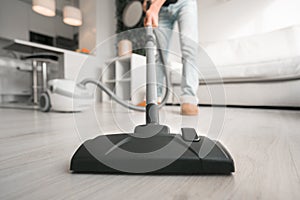 Man using a vacuum cleaner at home. Man cleaning house. House keeping concept. Close up on vacuum cleaner