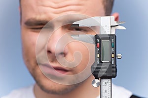 Man using vernier caliper on blue background.