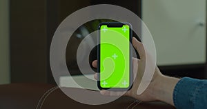 Man using vertical smartphone with green screen. Close-up shot of man`s hands with mobile phone. Chroma key. Close up.