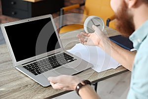 Man using video chat on laptop in home office. Space for text