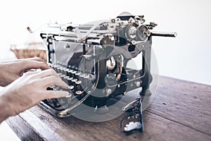 Man using vintage manual typewriter on rustic wooden table with motion blur due to carriage return