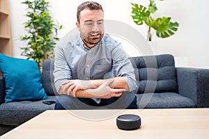 Man using virtual assistant and smart speaker at home