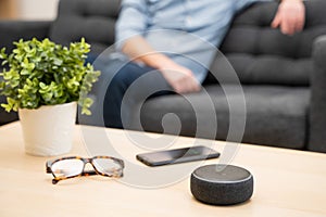 Man using virtual assistant and smart speaker at home