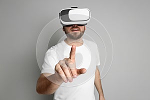 Man using virtual reality headset against light grey background, focus on hand