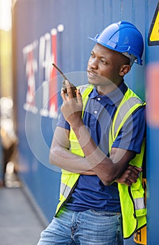 Man Using Walkie Talkie At Container Terminal, Industrial worker is controlling container loading