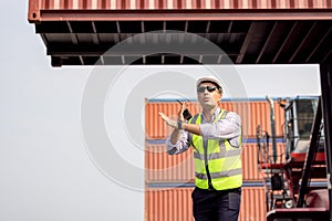 Man Using Walkie Talkie At Container Terminal, Industrial worker is controlling container loading