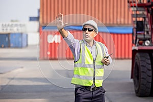 Man Using Walkie Talkie At Container Terminal, Industrial worker is controlling container loading