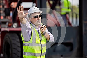 Man Using Walkie Talkie At Container Terminal, Industrial worker is controlling container loading