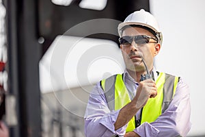 Man Using Walkie Talkie At Container Terminal, Industrial worker is controlling container loading