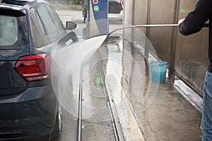 Man Using Water Pressure Machine to Wash a Car