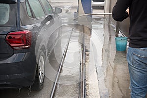 Man Using Water Pressure Machine to Wash a Car